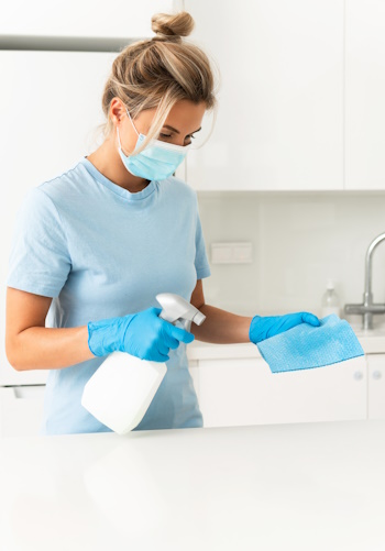 Young woman worker wearing prevention mask and gloves during apartment cleaning